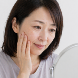 顔のしわ・たるみを気にして鏡を見る女性