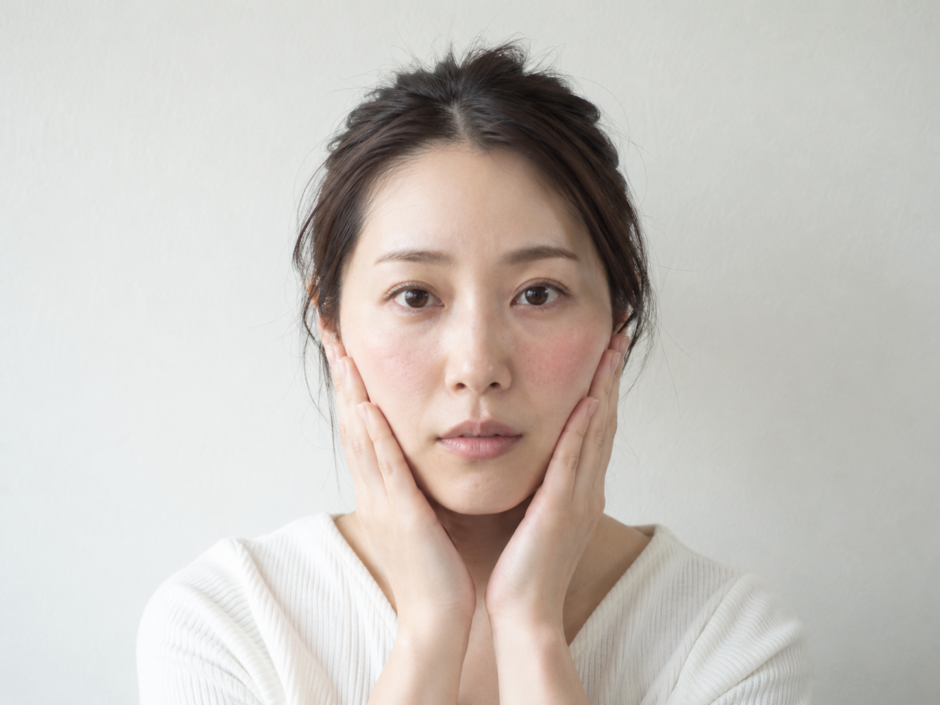 赤みのある頬に両手を添えている女性