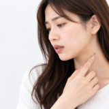 首のできものを気にして触れている女性
