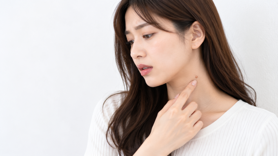 首のできものを気にして触れている女性