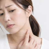 首のイボを気にして触れている女性