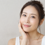 自分の頬を触って微笑む女性