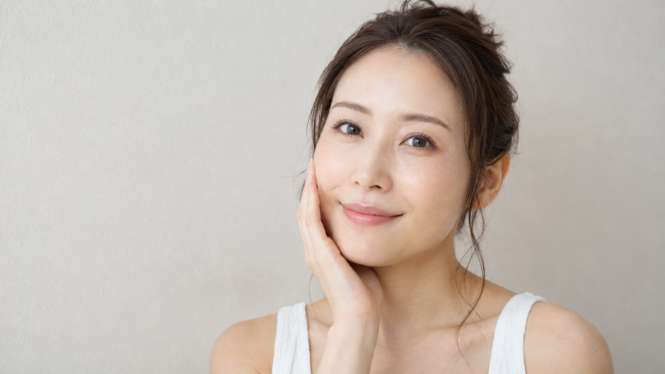 自分の頬を触って微笑む女性